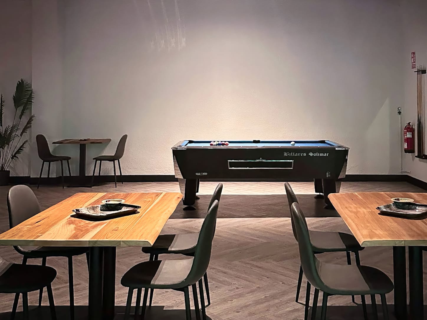 L'espace de divertissement du club de cannabis Four Twenty &agrave; Valence, comprenant un billard classique Billares Solimar sous un &eacute;clairage d'ambiance, entour&eacute; de tables en bois et de chaises.