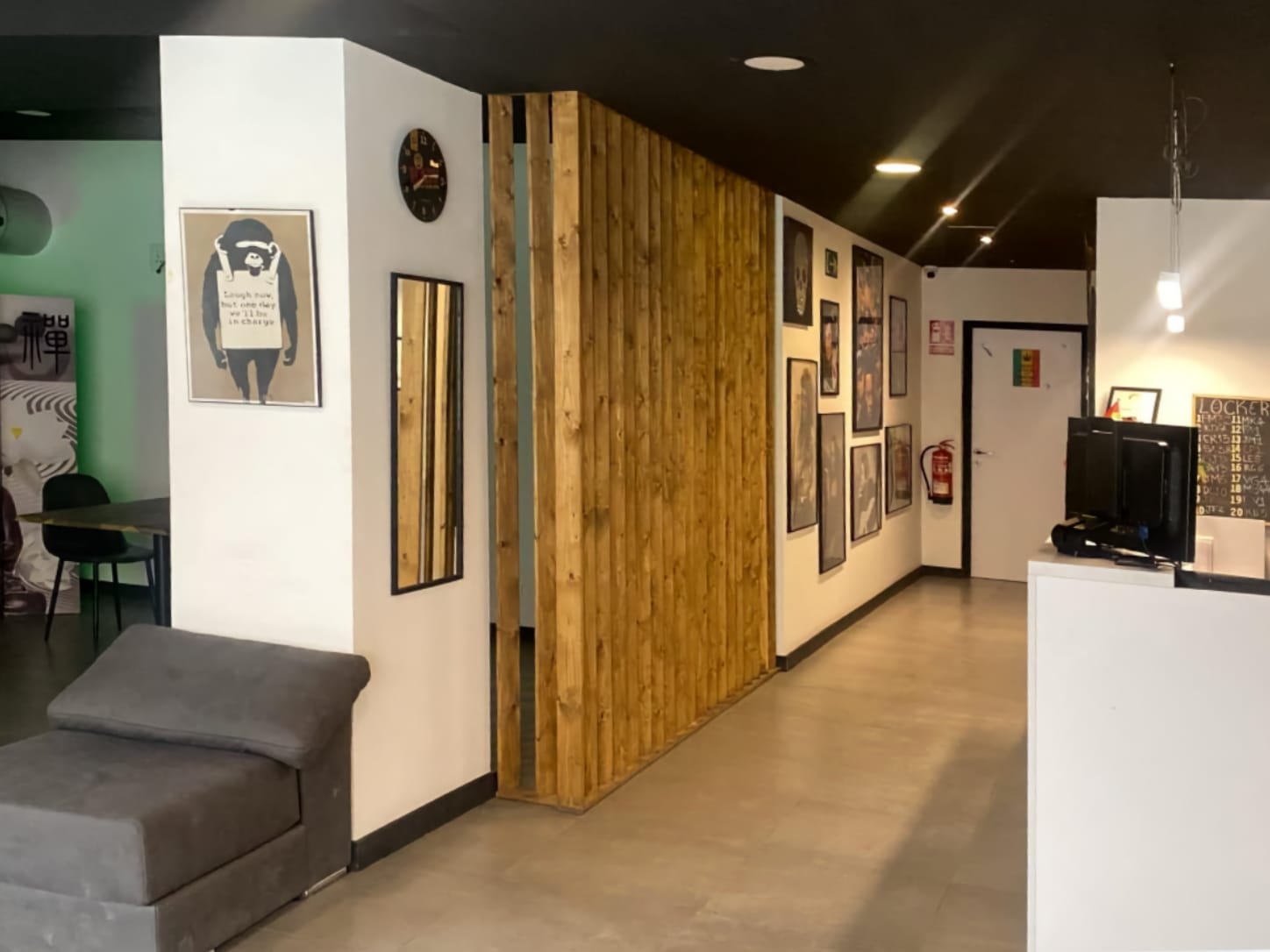 Le comptoir de r&eacute;ception et l'int&eacute;rieur moderne du club de cannabis Four Twenty &agrave; Valence, avec une cloison en lattes de bois, des tableaux encadr&eacute;s et un fauteuil gris.