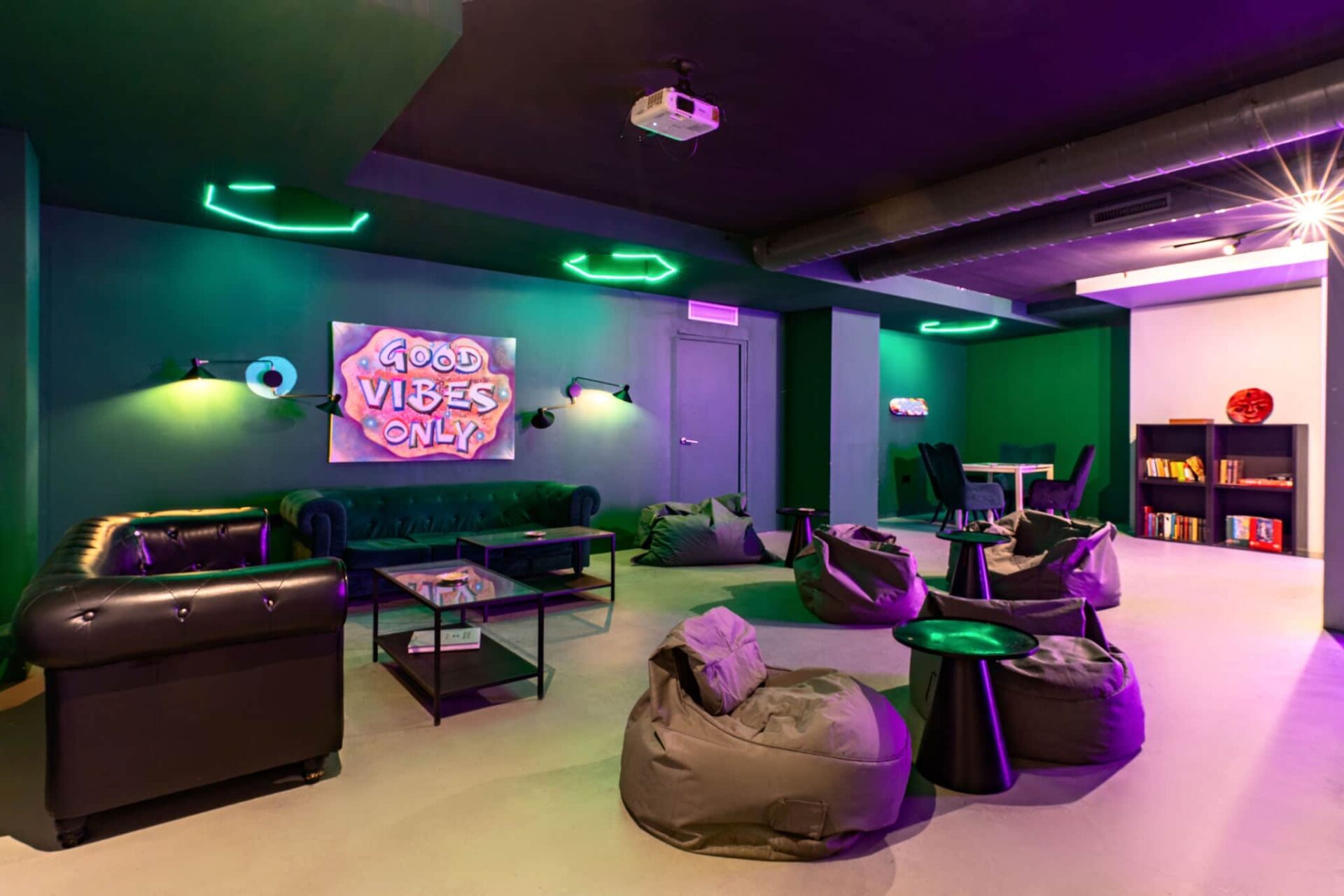 Espace lounge confortable du club social Gusto Green à Barcelone avec poufs et lumières néon
