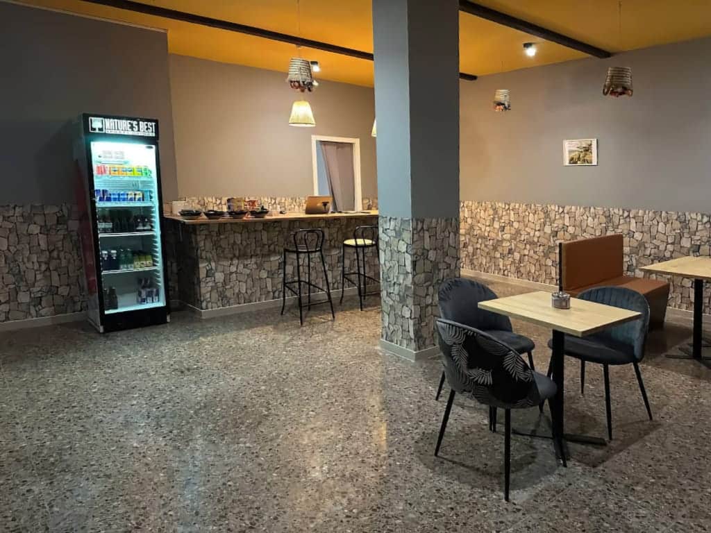 Intérieur du club de cannabis Magura à Valence, avec un comptoir en pierre texturée, un sol en terrazzo, des sièges modernes et un réfrigérateur à boissons.