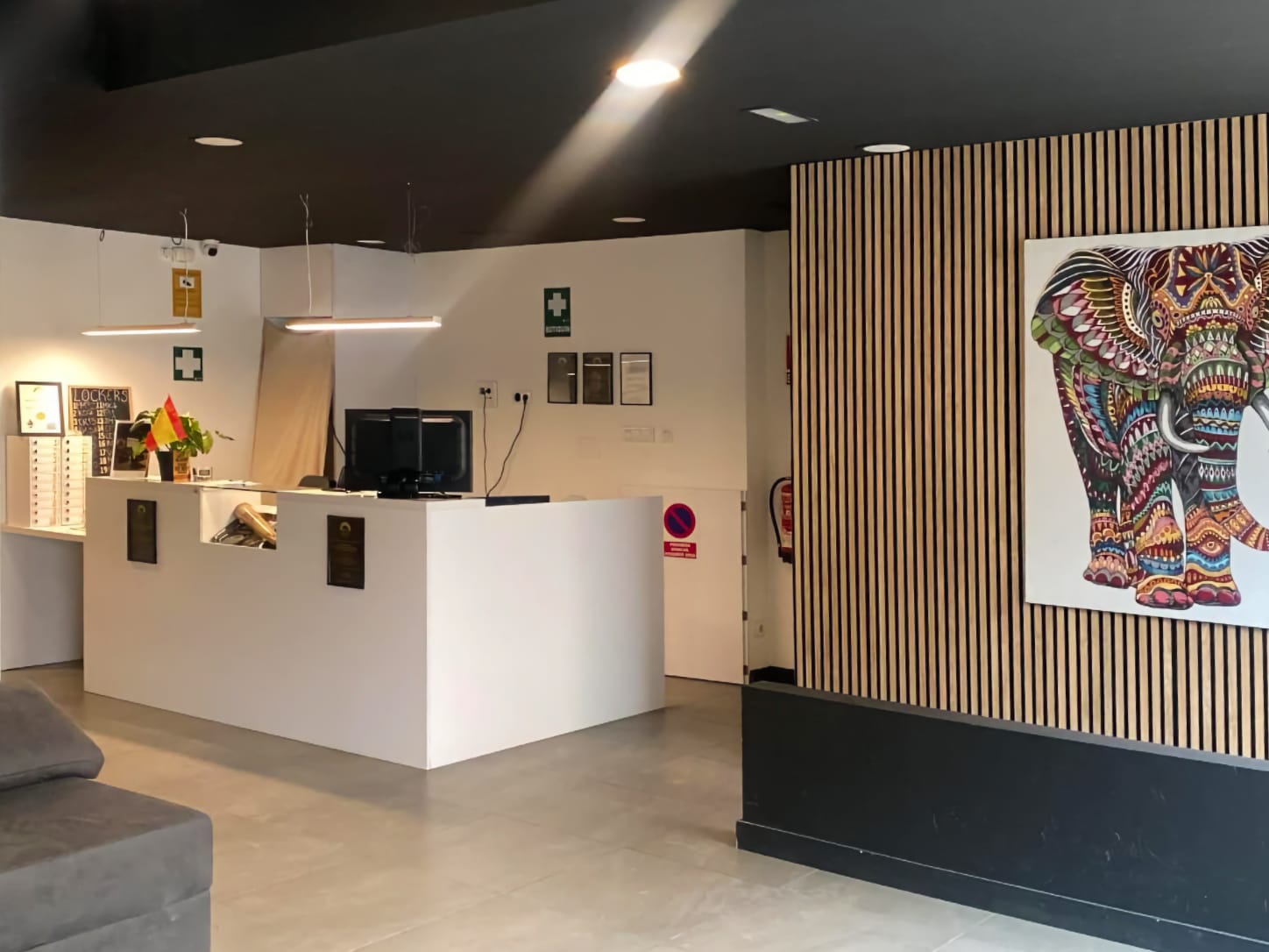 Le comptoir de r&eacute;ception blanc minimaliste du club de cannabis Four Twenty &agrave; Valence, avec un &eacute;clairage moderne et un tableau d'&eacute;l&eacute;phant color&eacute; sur un mur en lattes de bois.