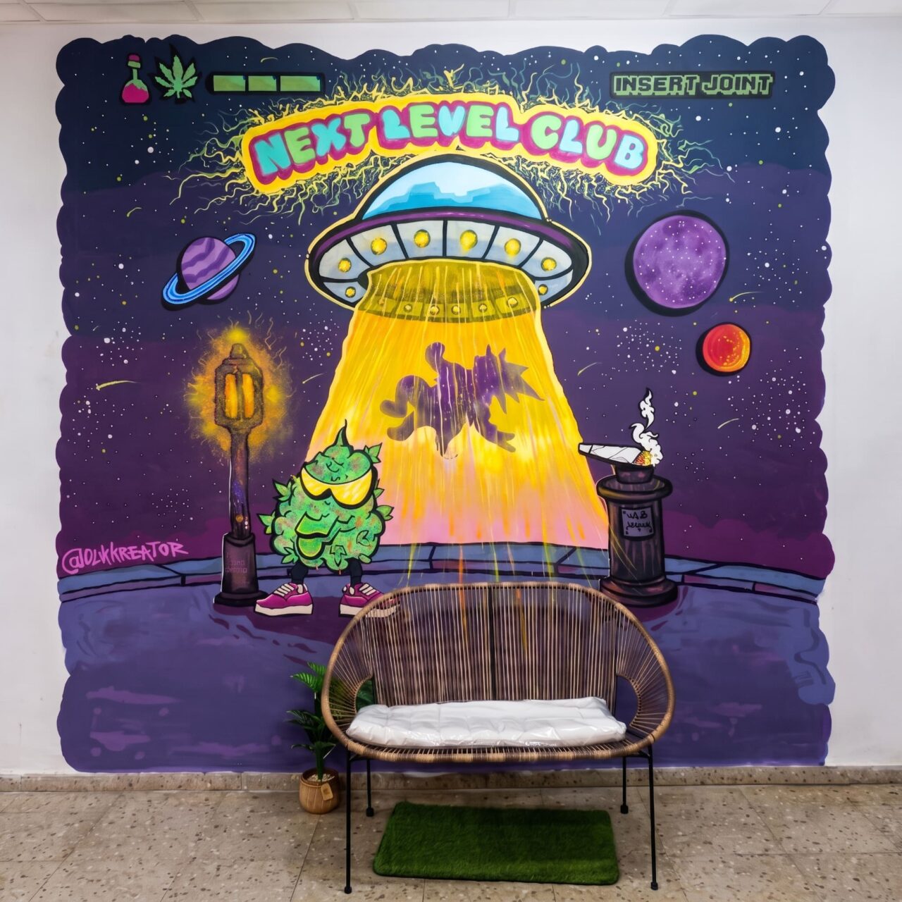 Int&eacute;rieur du cannabis club Next Level Club &agrave; Valence : un banc tress&eacute; devant un graffiti d'OVNI.